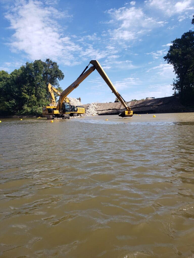 A truck excavating on the banks of a river.