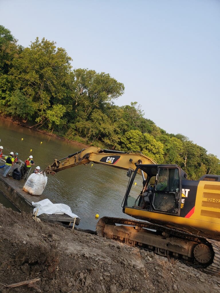 Workers on a river dock next to a truck.
