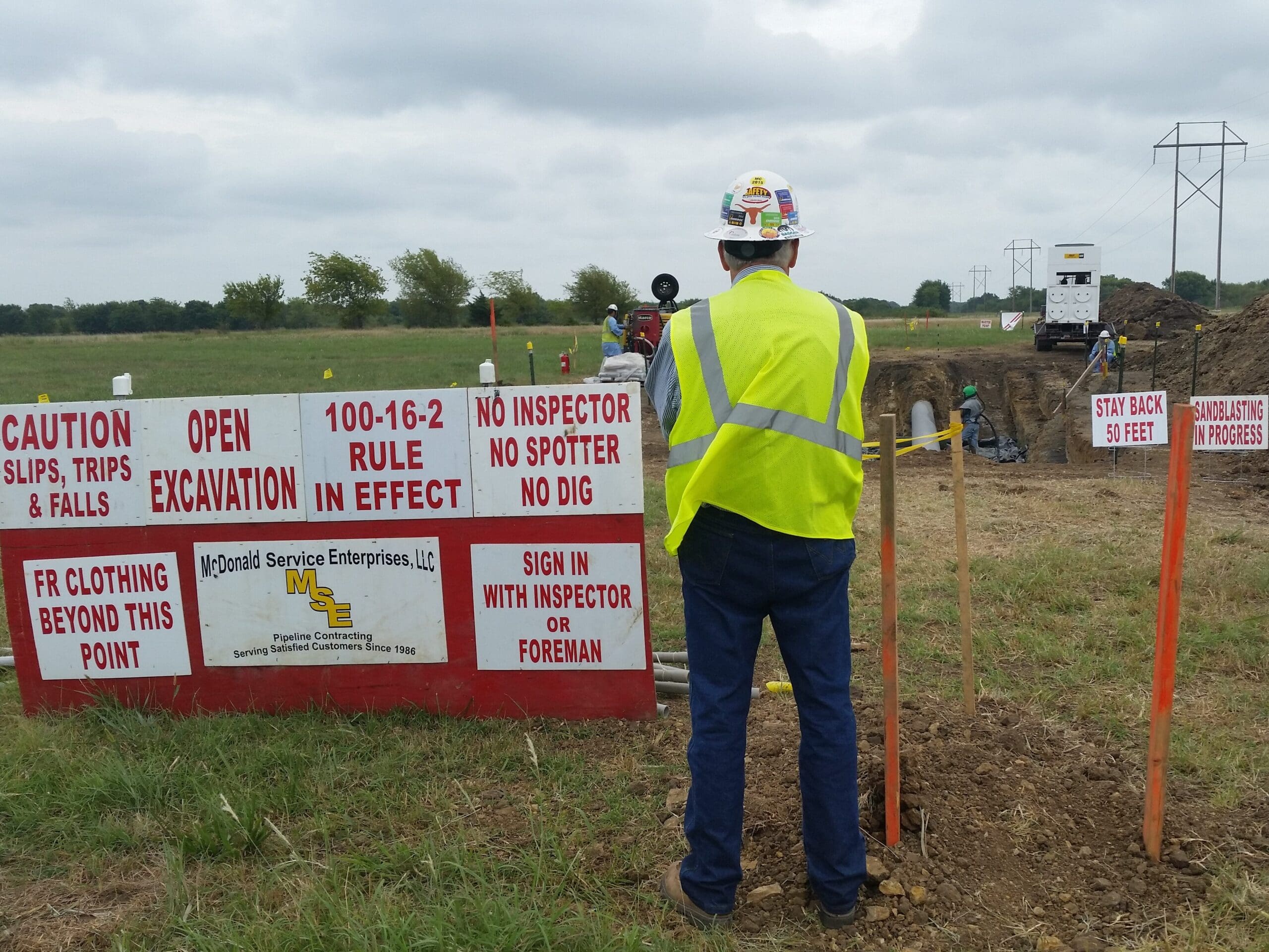 A worker with his back turned in front of a sign with safety reminders.
